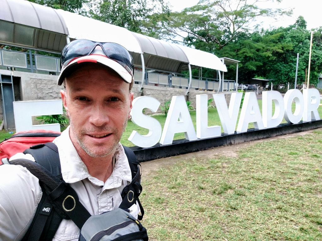 nomadic backpacking arriving at San Salvador airport in front of the EL Salvador sign